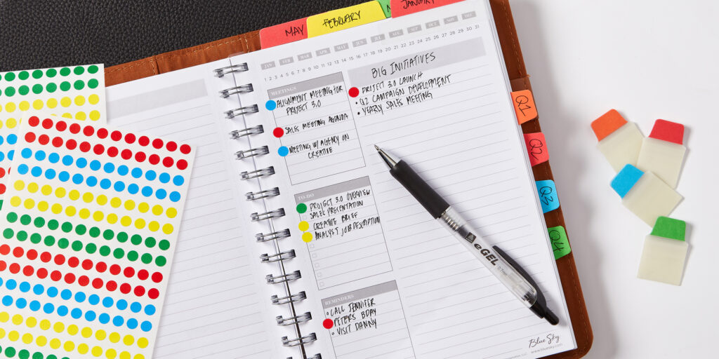 Close up of an open planner for work. The planner is organized with color-coding labels and Avery Ultra Tabs.