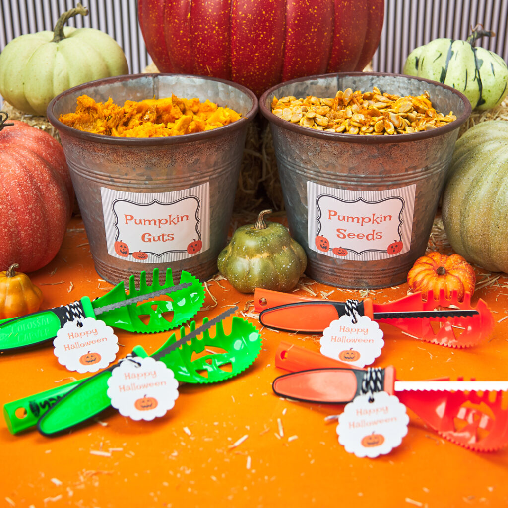 Pumpkin carving supplies and seed buckets are surrounded by green, orange and white pumpkins. The buckets and supplies are labeled with Avery cards and tags. 