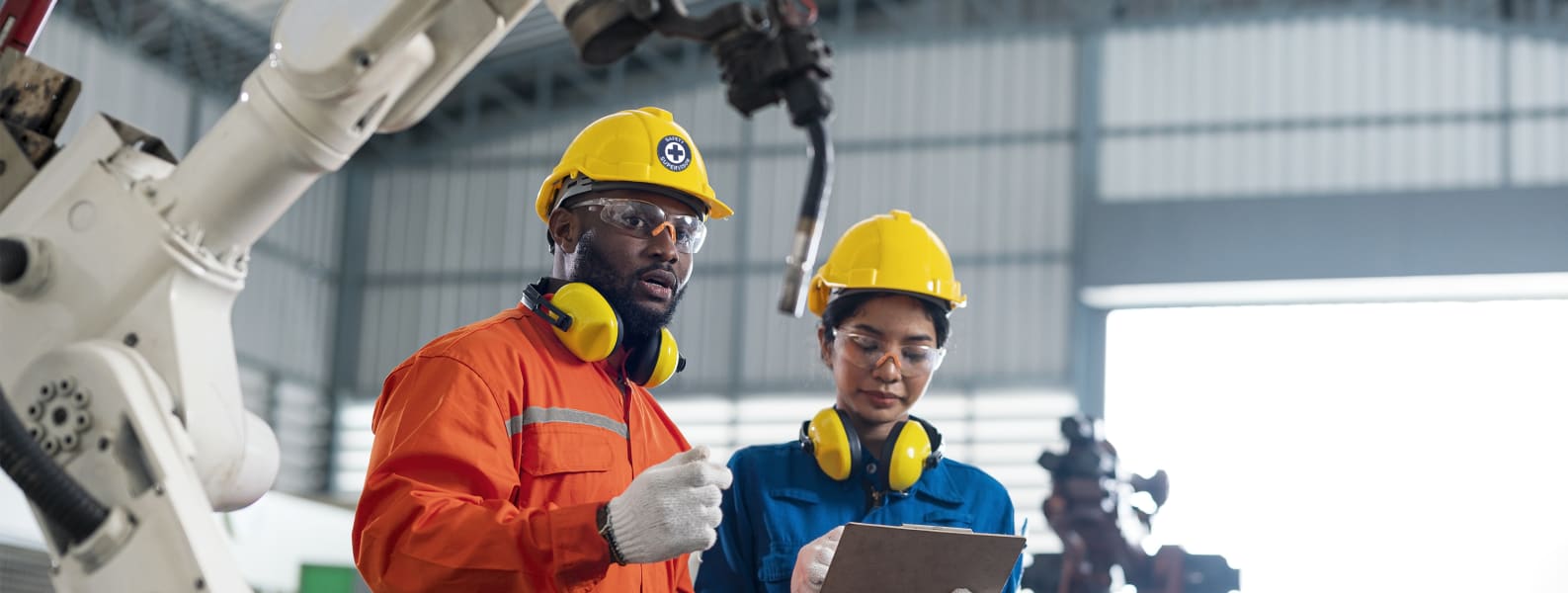 Image of two Industrial workers in safety gear looking at a clipboard